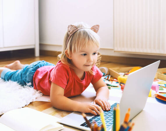 Little girl using computer online technology at home